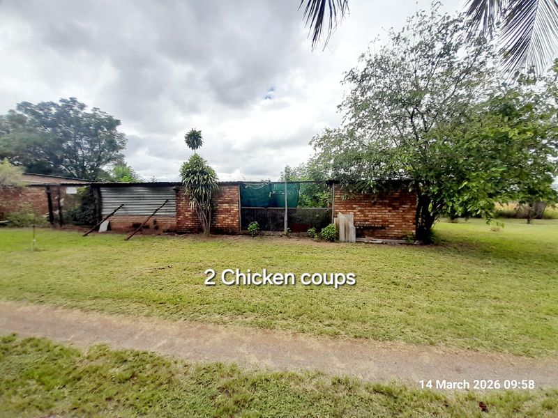 Exterior view of two farm chicken coops featuring brick construction and wire mesh enclosures situated on a grassy plot.