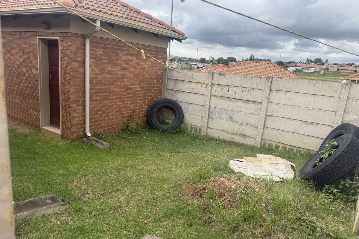A rear garden area featuring a brick outbuilding with a tiled roof and perimeter precast concrete walling.