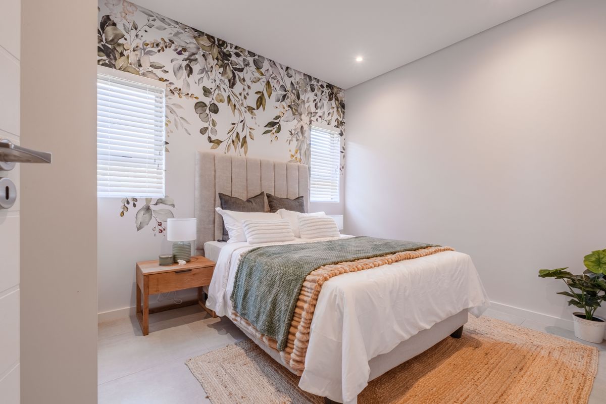 A well-lit bedroom featuring neutral tiled flooring, recessed ceiling lighting, and dual windows with fitted venetian blinds.