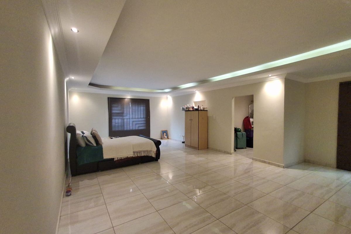 Spacious bedroom featuring large format floor tiles, recessed ceiling lighting, and an integrated walk-in closet area.