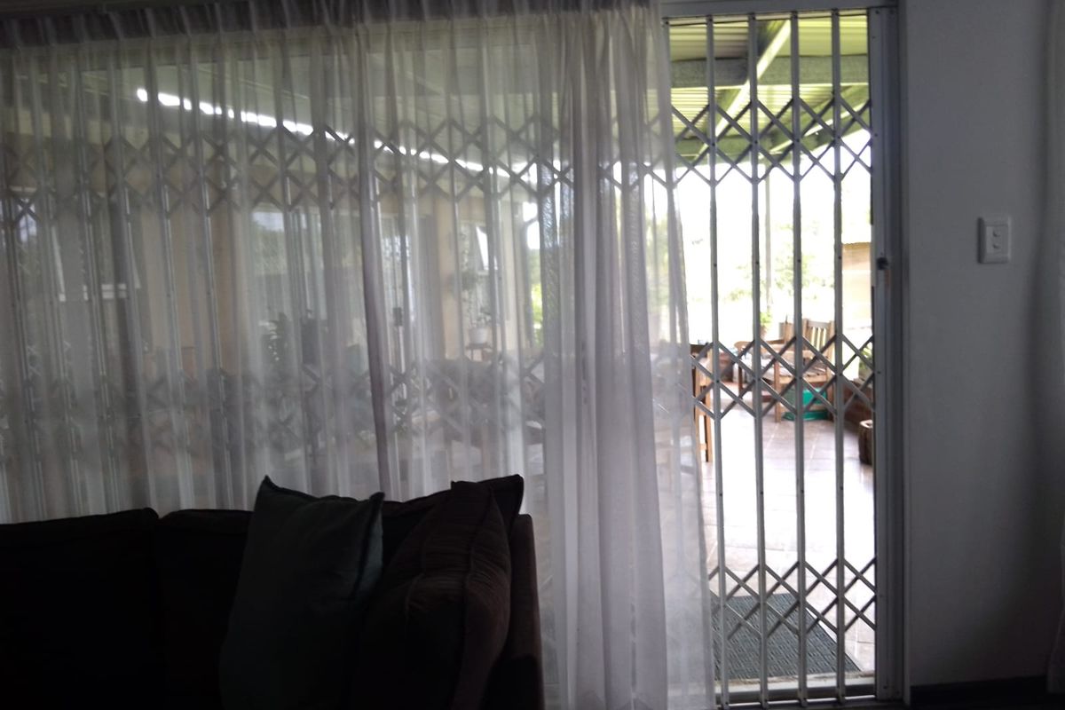 View from the living area looking out through a security gate onto a covered patio space.