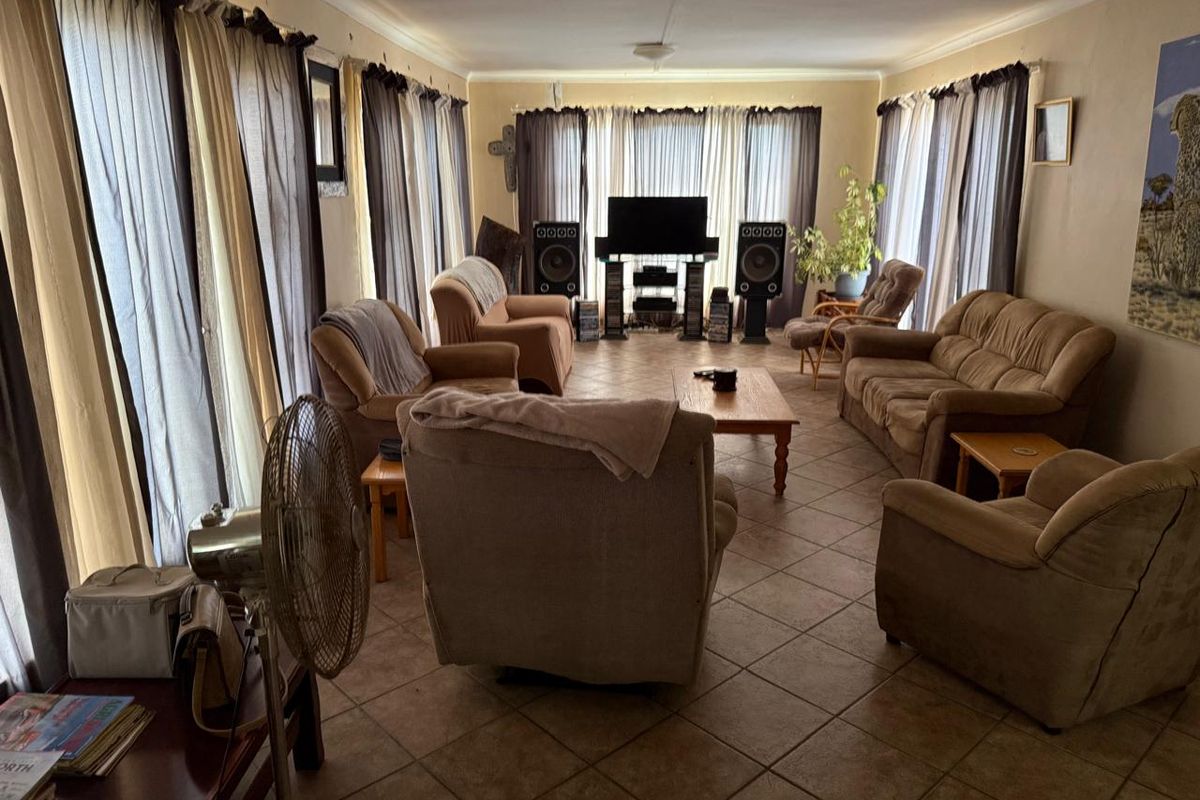Spacious living room featuring tiled flooring and large windows, offering a functional layout with potential for modern updates to enhance the interior aesthetic.
