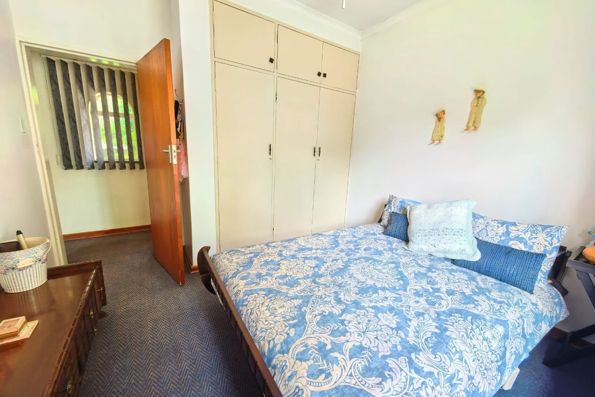 A bedroom featuring built-in cupboards and carpeted flooring, with an adjacent doorway leading to a secondary space.