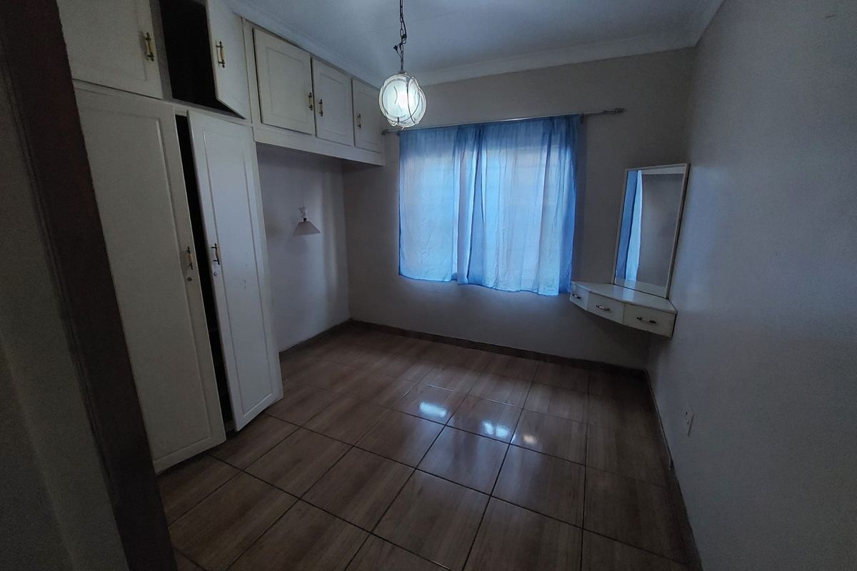 A bedroom featuring built-in cabinetry, tiled flooring, and a wall-mounted vanity unit.