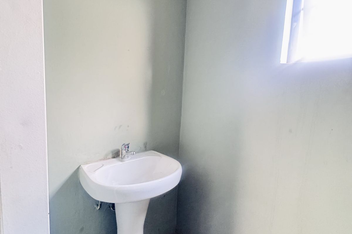 A small, functional cloakroom or powder room featuring a white pedestal basin and tiled flooring.