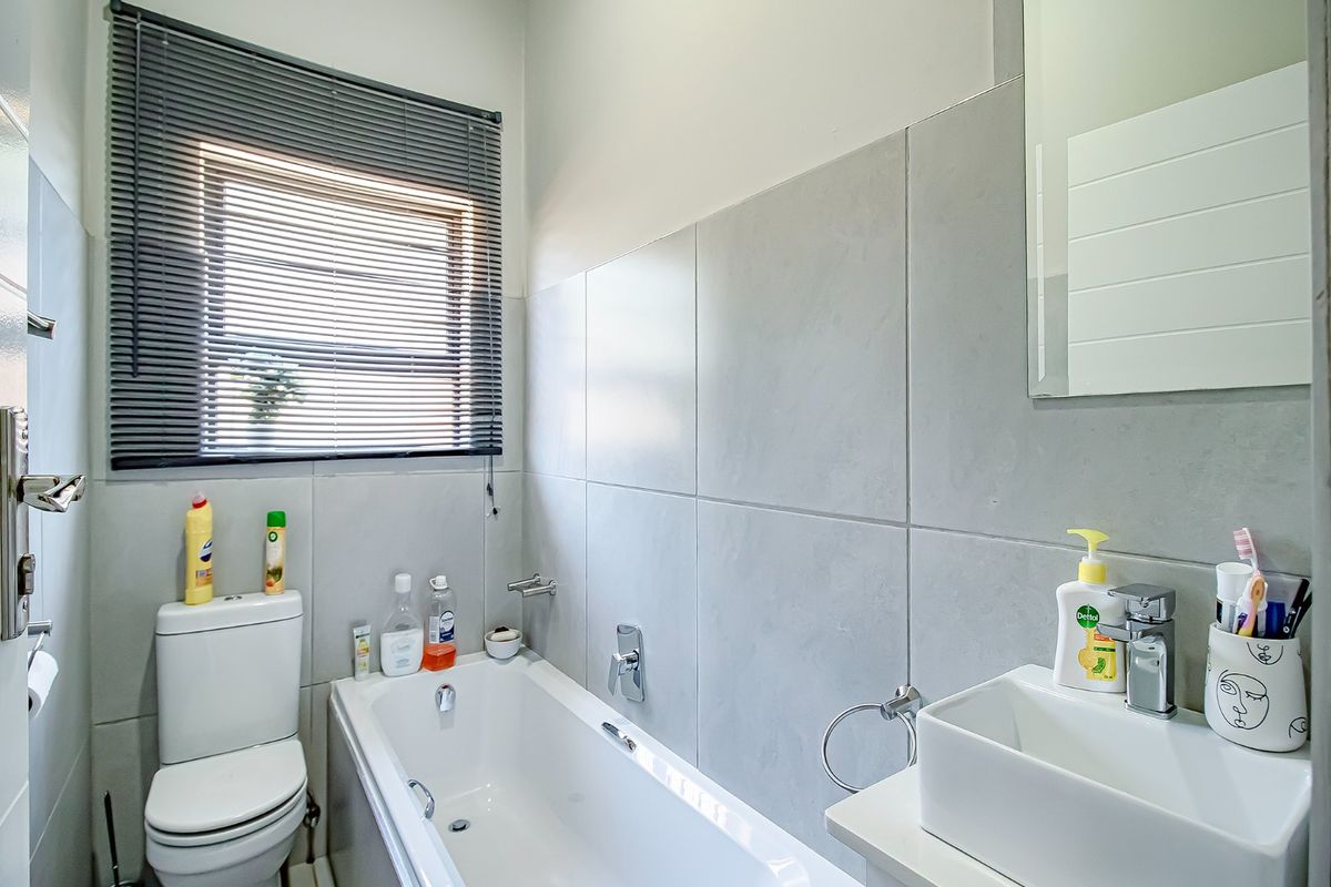 A compact, modern bathroom featuring a built-in bathtub, wall-mounted toilet, and a contemporary vessel sink with chrome fixtures.