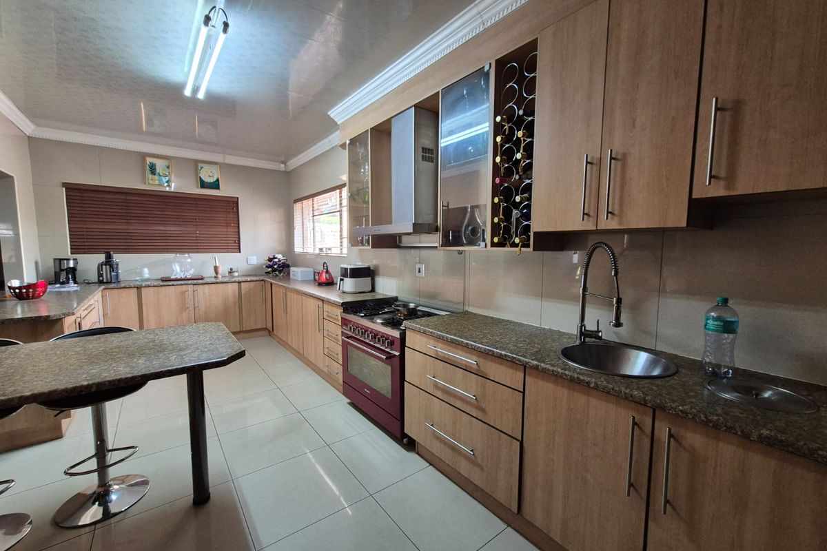 Spacious kitchen featuring wood-finish cabinetry, granite countertops, a built-in gas stove with extractor fan, and a breakfast bar island.