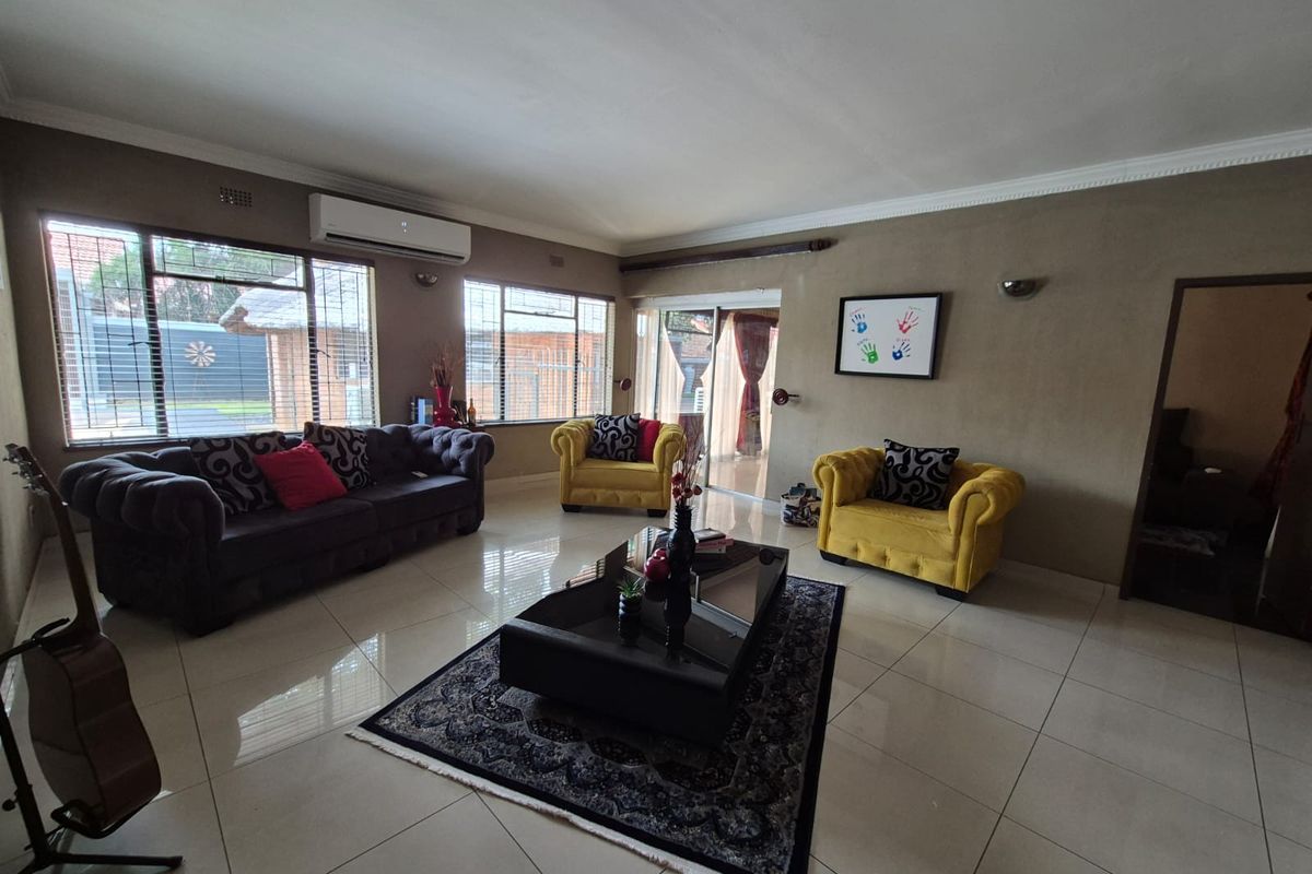Spacious living room featuring large windows, tiled flooring, and a wall-mounted air conditioning unit.
