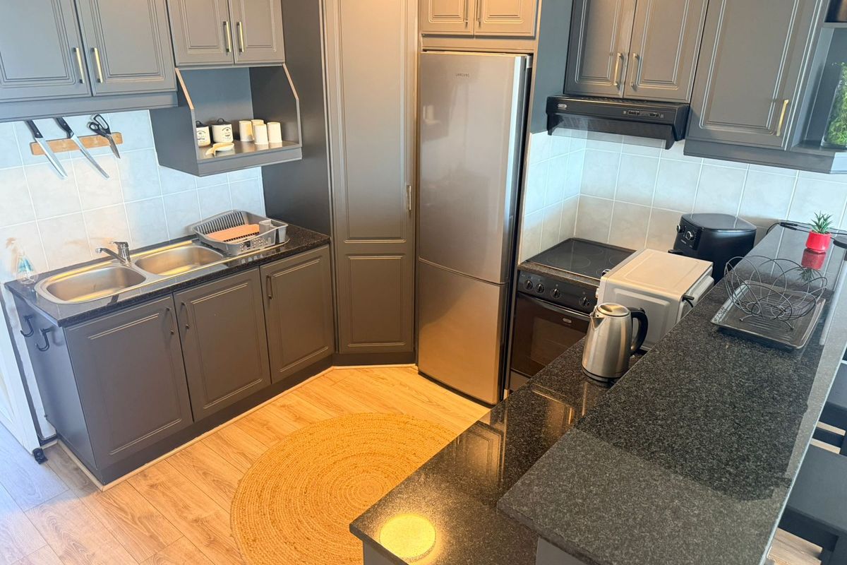Modern kitchen featuring dark grey cabinetry, granite countertops, double stainless steel sink, and integrated oven with extractor fan.