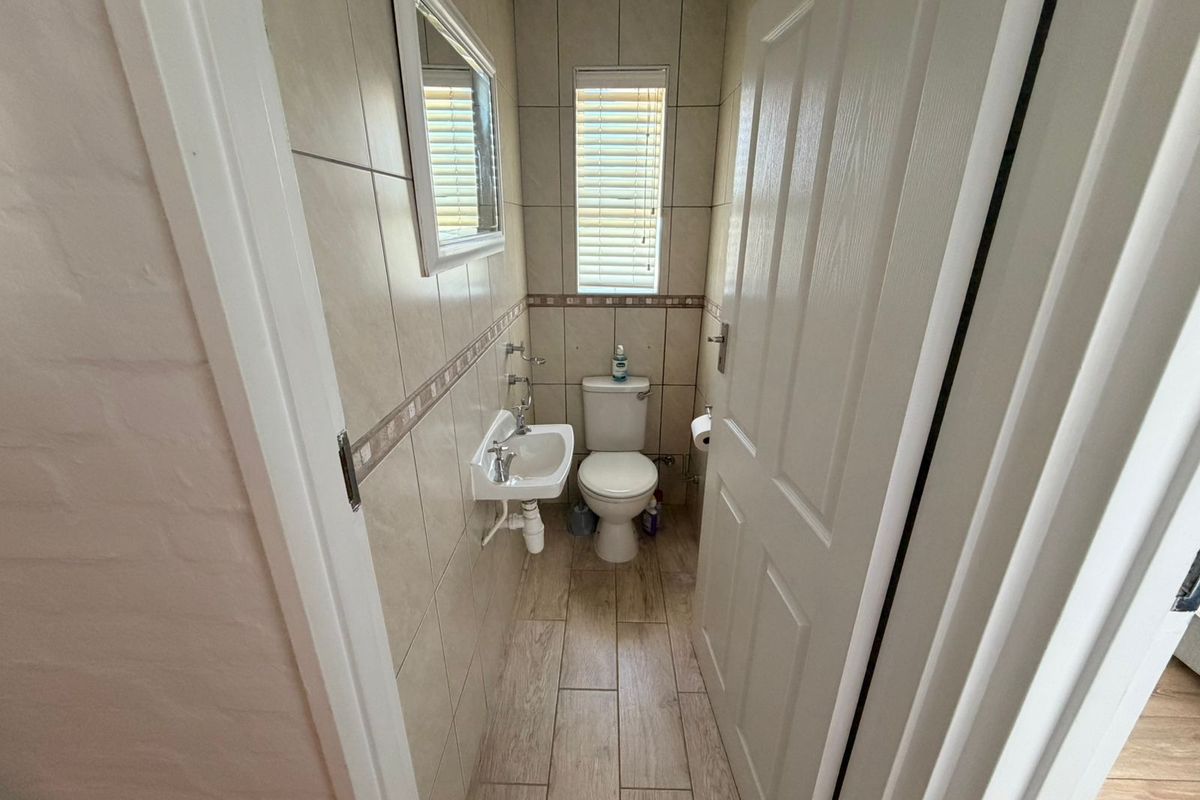 A compact guest bathroom featuring floor-to-ceiling wall tiles, a wall-mounted basin, and a standard toilet.