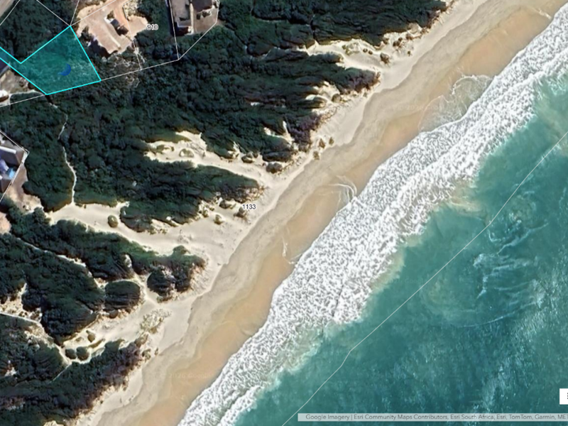 Aerial view of a vacant residential plot situated along the coastline, offering direct proximity to the beach and natural dune vegetation.