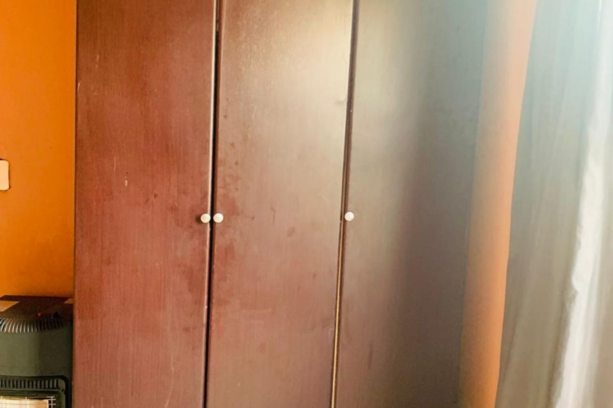 A bedroom interior featuring a large built-in dark wood wardrobe and tiled flooring.