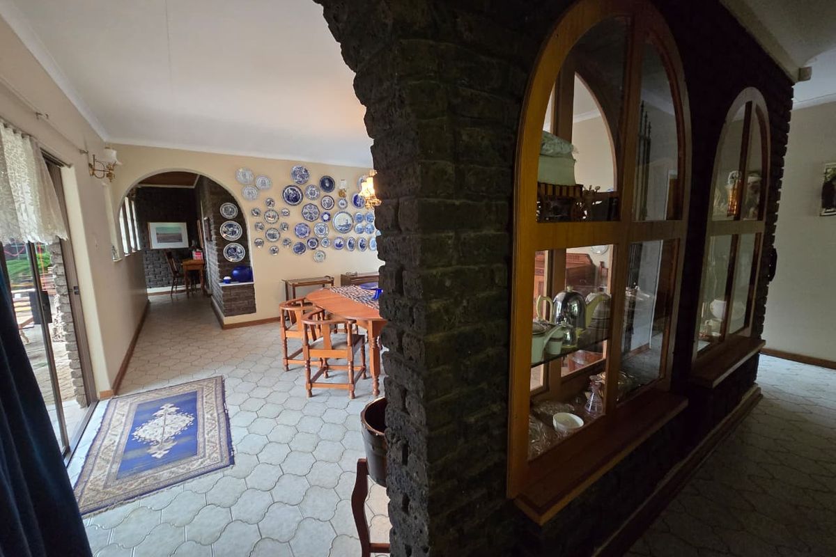 Spacious living area featuring exposed brick archways, built-in display cabinetry, and tiled flooring, creating a rustic and character-filled interior space.