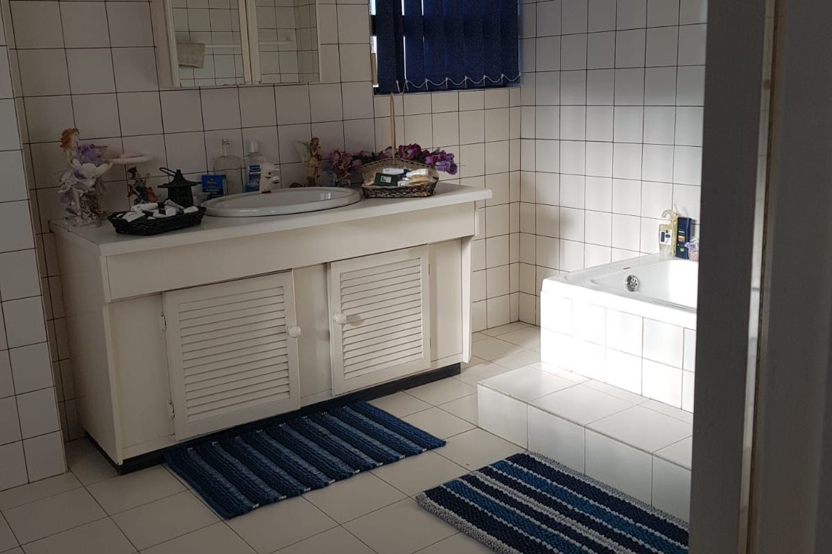 A functional bathroom featuring a built-in vanity with basin, a tiled bathtub, and full-height wall tiling.