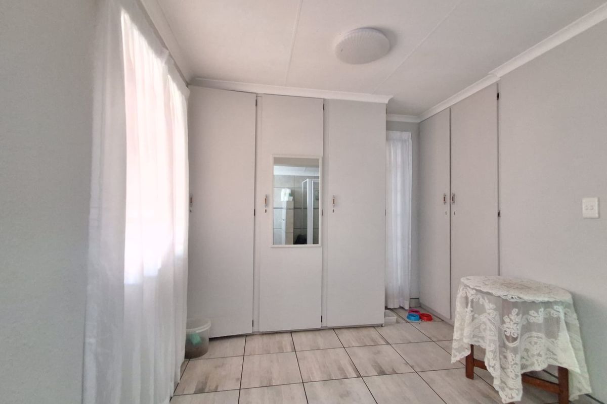 A bedroom featuring built-in cupboards with a central mirror and tiled flooring.