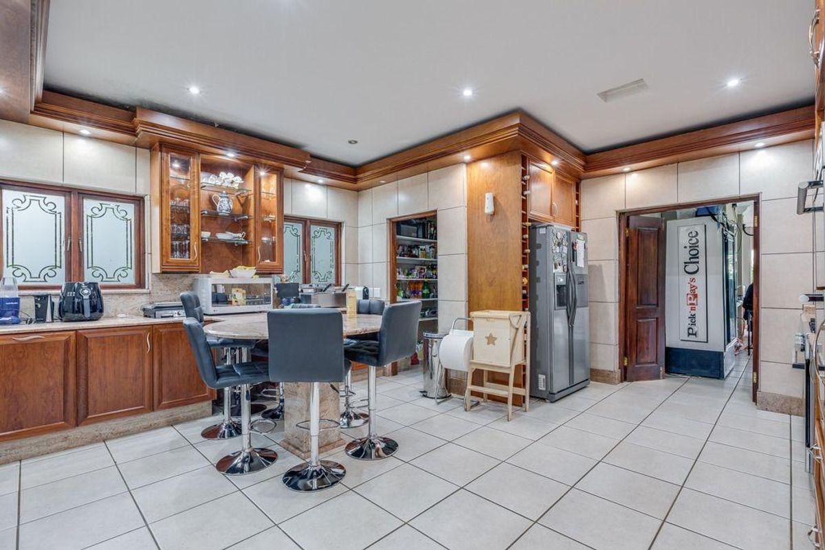 Spacious kitchen featuring extensive wooden cabinetry, integrated storage, tiled flooring, and a central breakfast bar area with recessed lighting.