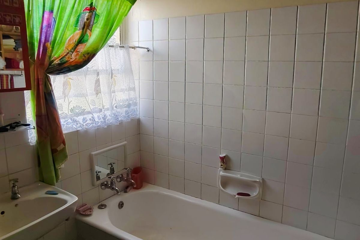 A dated bathroom featuring a standard bathtub, wall-mounted basin, and tiled splashbacks, requiring modernization to improve its overall condition and aesthetic appeal.