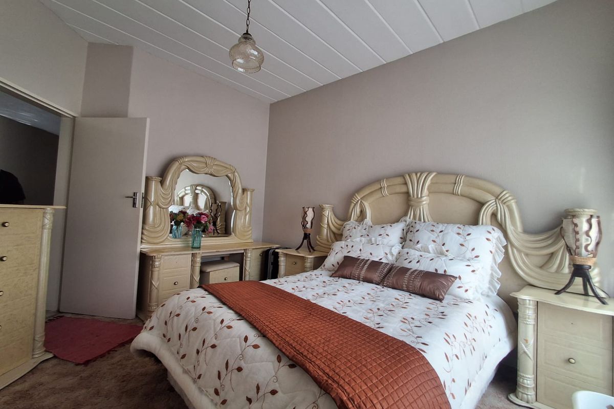 A bedroom featuring a panelled ceiling and neutral wall tones, providing a functional and comfortable sleeping space.