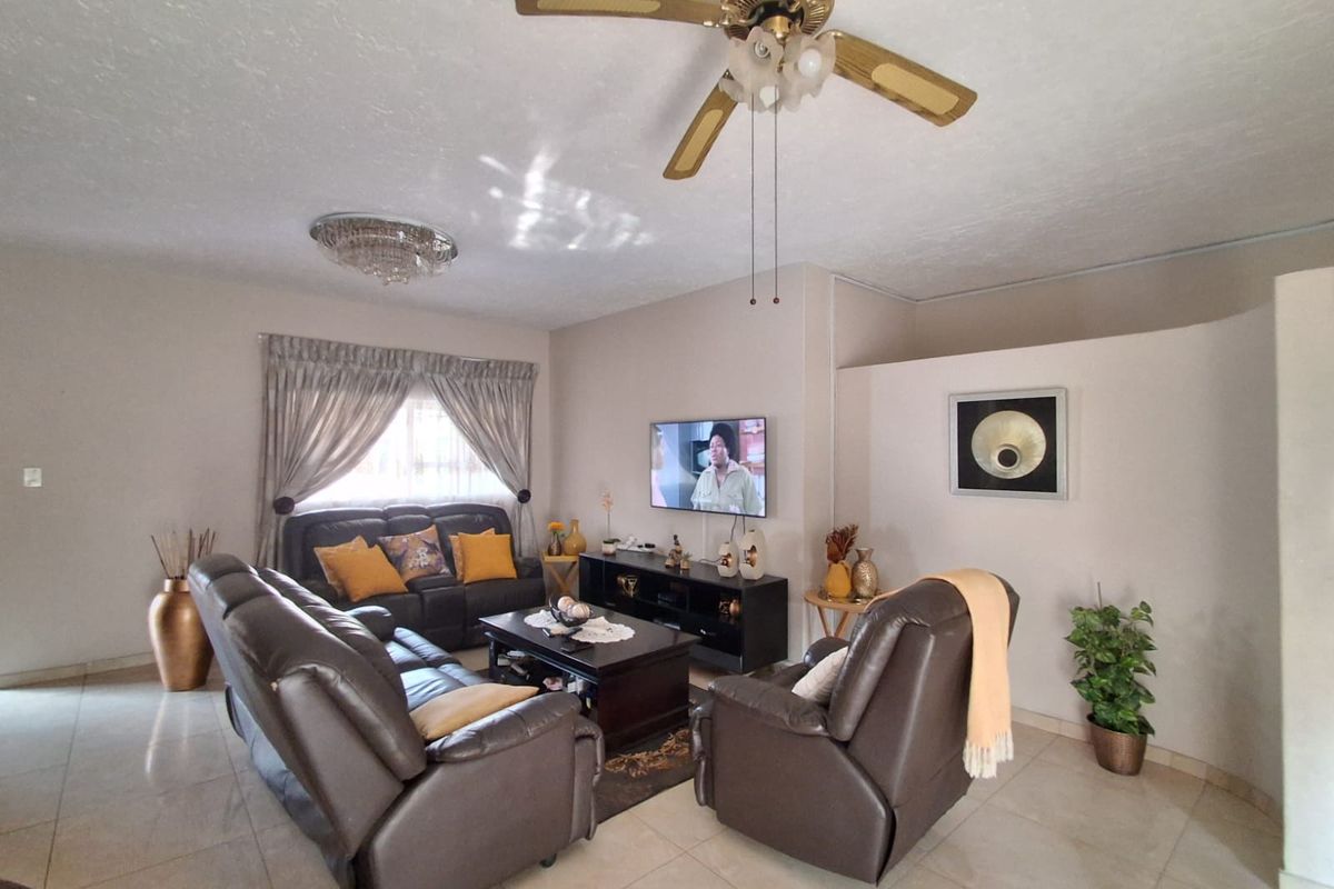 A comfortable living room featuring tiled flooring, a ceiling fan, and a partition wall creating a defined lounge area.