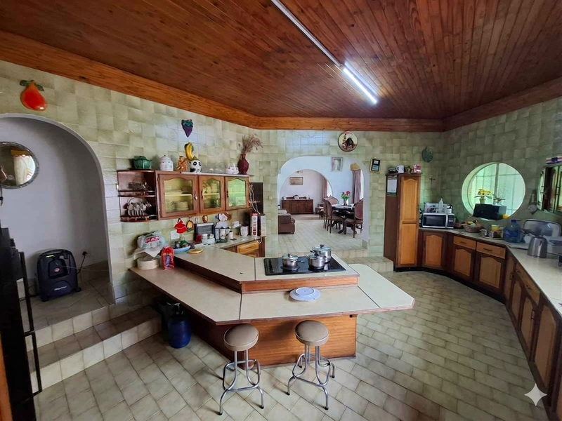 Spacious kitchen featuring a raised breakfast bar, integrated hob, timber ceiling, and distinctive archways leading to the adjacent living and dining areas.