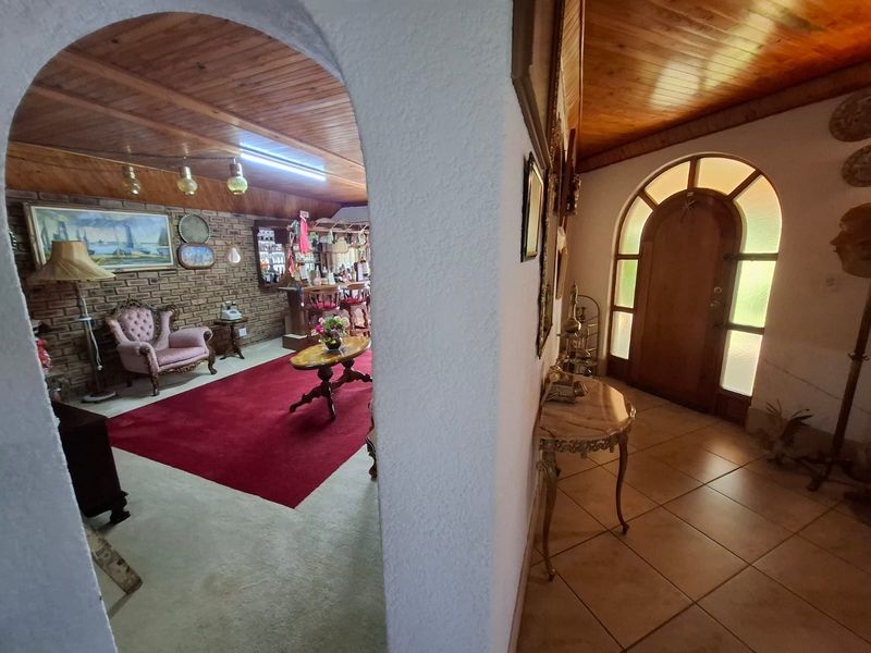 Entrance hall featuring tiled flooring and an arched timber front door, leading into an open-plan living area with exposed brickwork and a built-in bar.