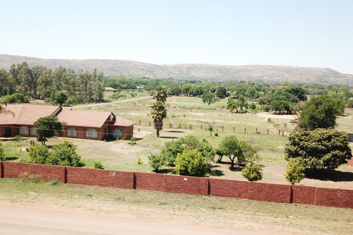 Aerial view of a small holding property featuring a brick-built house with a tiled roof, large garden, and perimeter walling.
