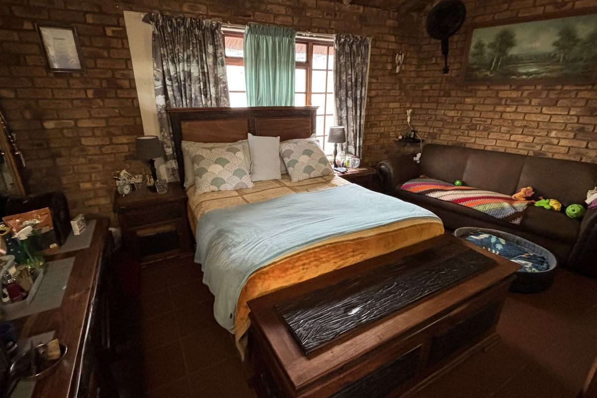 A rustic bedroom featuring exposed brick walls, tiled flooring, and a window with natural light.
