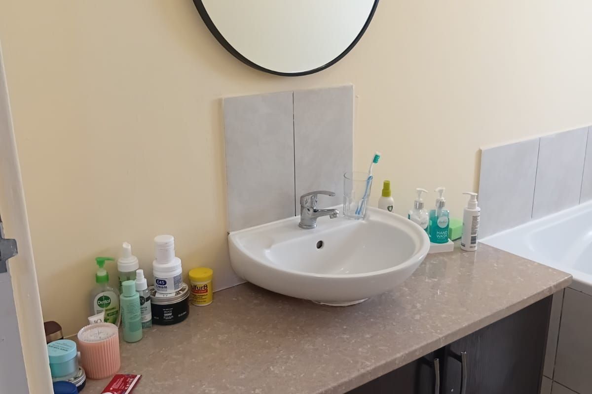 A functional bathroom vanity featuring a modern vessel sink, dark cabinetry, stone-look countertop, and a circular wall-mounted mirror.