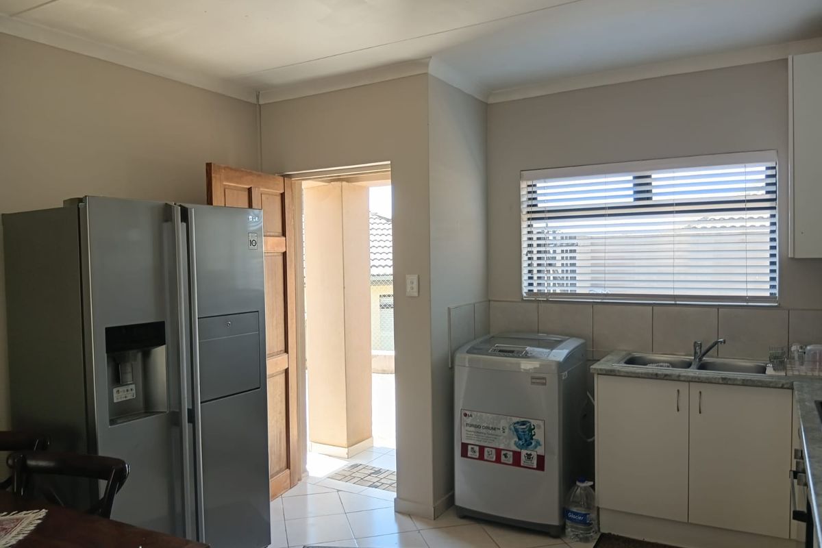 A functional kitchen and laundry area featuring built-in cabinetry, a stainless steel sink, and direct access to an outdoor patio space.