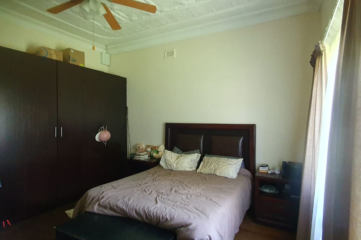 A bedroom featuring built-in dark wood cabinetry, a decorative pressed metal ceiling, and a ceiling fan.