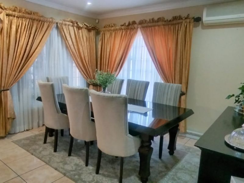 A dining room featuring tiled flooring, crown molding, and a wall-mounted air conditioning unit.