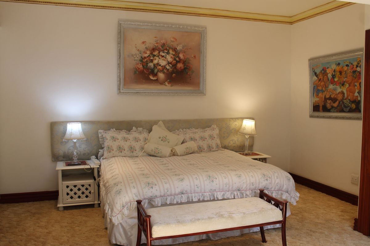 A bedroom featuring a neutral color palette, an upholstered headboard, and decorative crown molding.