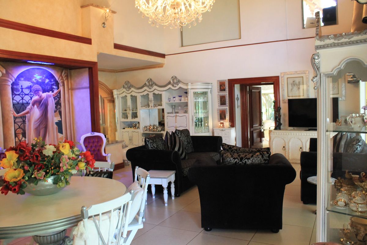 Spacious living area featuring high vaulted ceilings, a large crystal chandelier, and neutral tiled flooring with integrated display cabinetry.