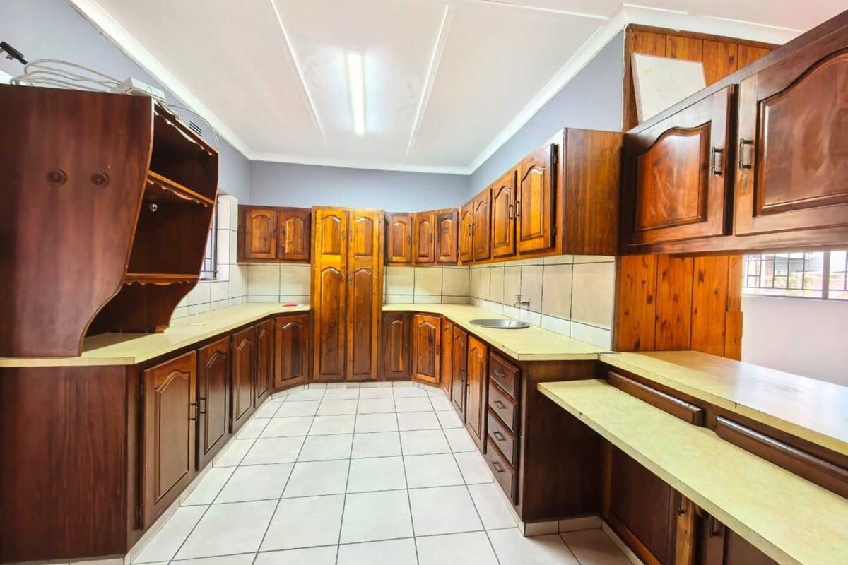 A spacious kitchen featuring extensive wooden cabinetry, tiled flooring, and ample laminate countertop workspace.