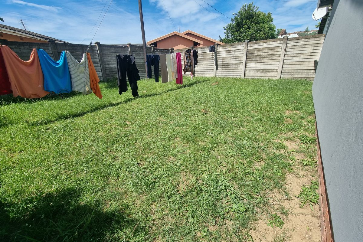 A rear garden area featuring a lawn and a concrete boundary wall, providing a private outdoor space for the property.