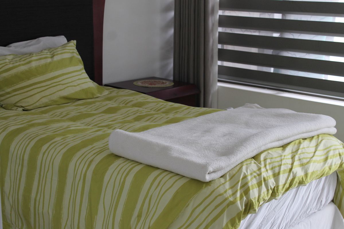 A bedroom featuring a built-in headboard and modern zebra-style window blinds.