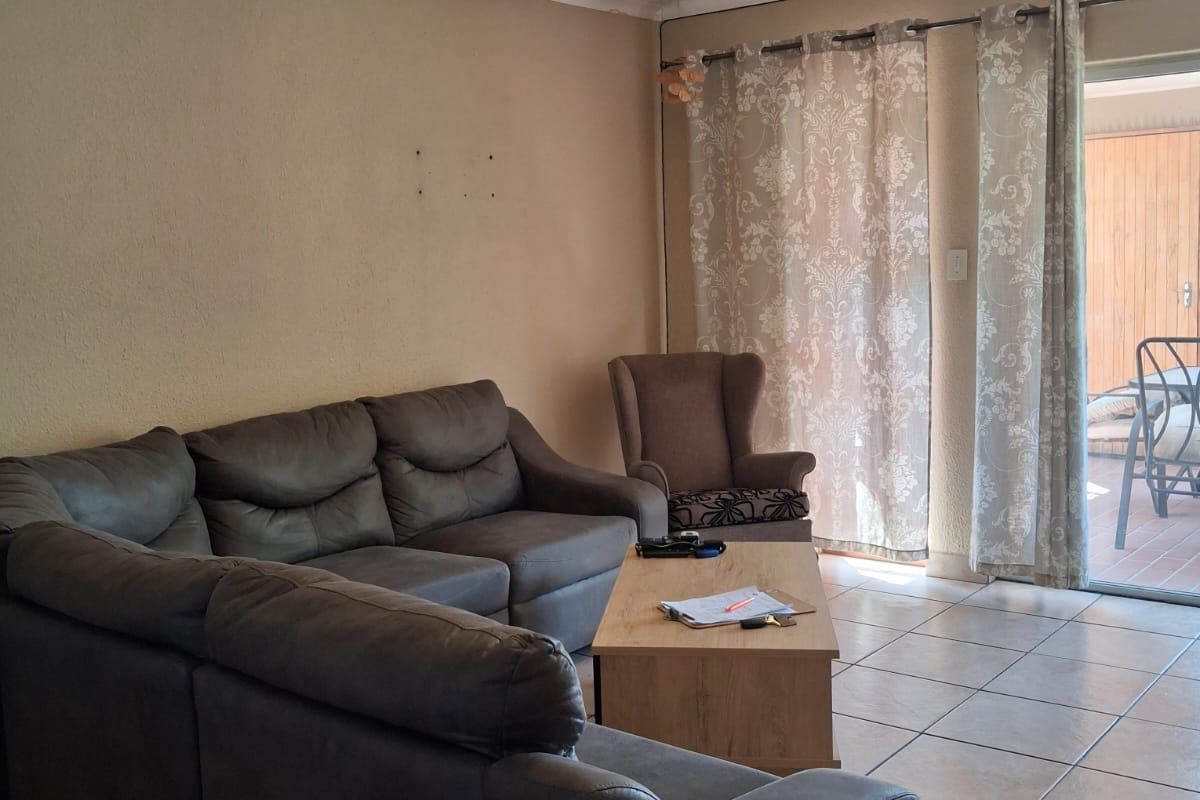 A living room featuring tiled flooring and sliding glass doors that provide access to an outdoor patio area.