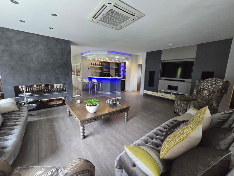 Spacious open-plan living area featuring a modern built-in fireplace, a dedicated bar area with ambient lighting, and a custom media wall.