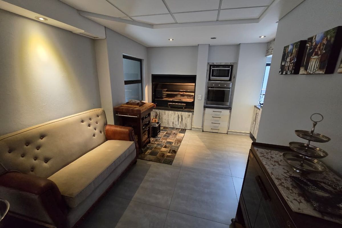 A functional kitchen area featuring a built-in braai, integrated oven and microwave, tiled flooring, and recessed lighting within a drop ceiling design.