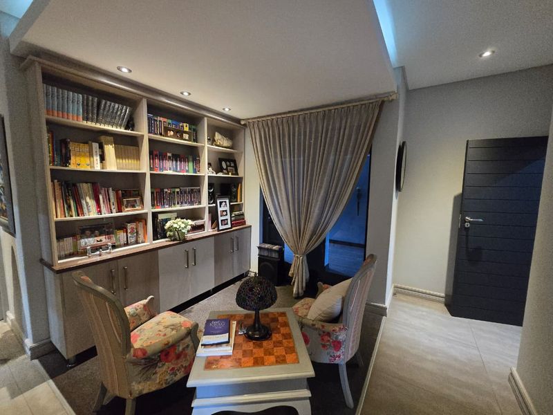 A cozy living area featuring extensive built-in cabinetry and shelving, recessed ceiling lighting, and modern tiled flooring.