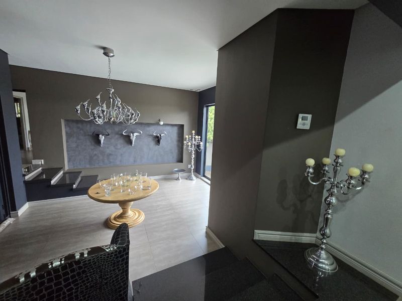 Spacious living area featuring modern tiled flooring, a recessed wall display feature, and a contemporary staircase with stone treads.