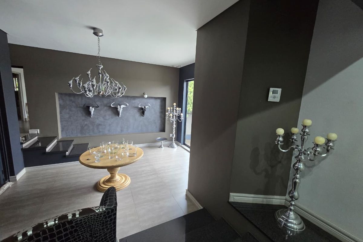 Spacious living area featuring modern tiled flooring, a recessed wall display feature, and a contemporary staircase with stone treads.