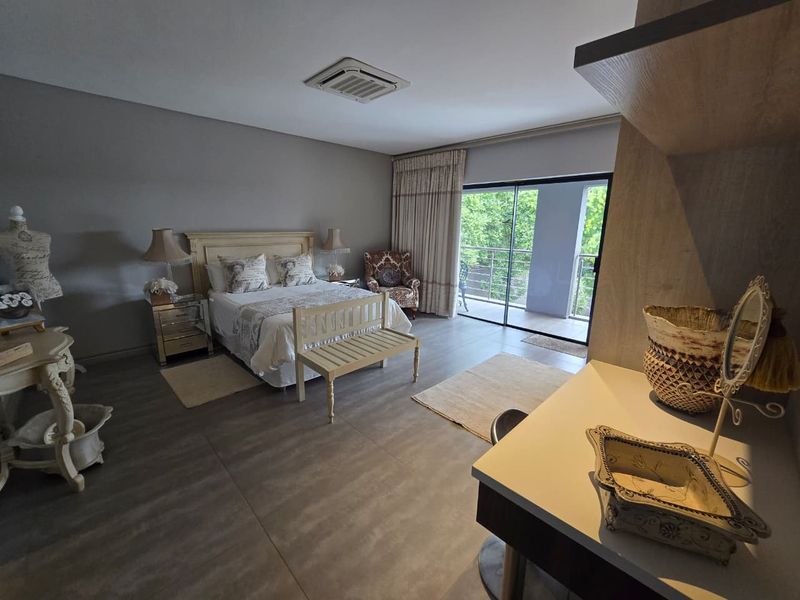 Spacious bedroom featuring large format floor tiles, a recessed ceiling air conditioning unit, and sliding glass doors leading to a private balcony.