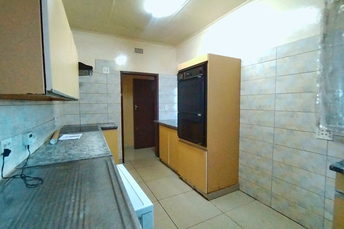 A functional kitchen featuring built-in cabinetry, a double sink, and a built-in oven, with tiled walls and flooring throughout.