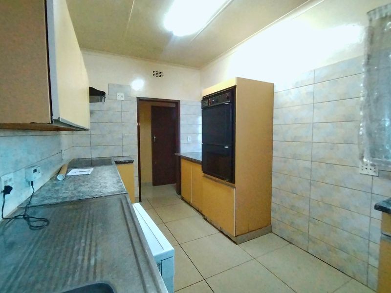 A functional kitchen featuring built-in cabinetry, a double sink, and a built-in oven, with tiled walls and flooring throughout.