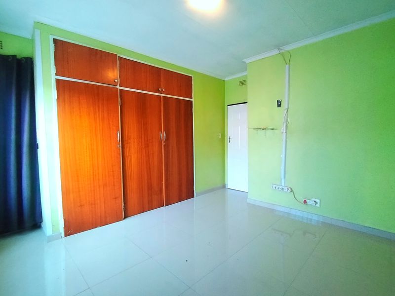 An empty bedroom featuring tiled flooring and built-in wooden cupboards, offering a blank canvas for personalization.