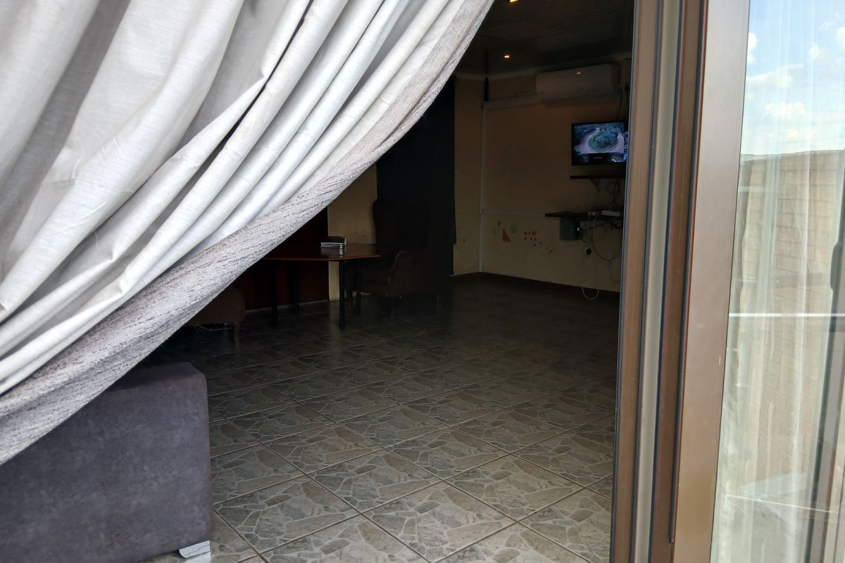 A view into a living area featuring tiled flooring, a wall-mounted air conditioning unit, and sliding door access to an outdoor space.