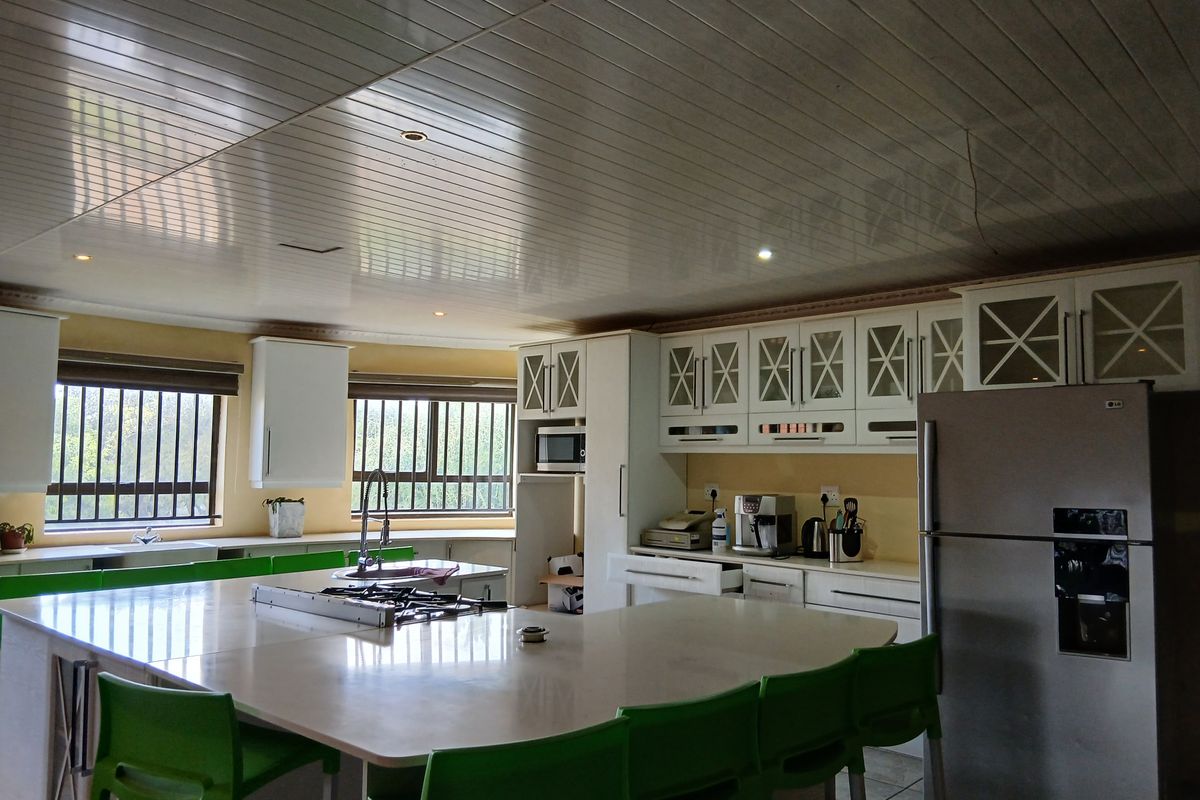 Spacious kitchen featuring a large central island with integrated gas hob, ample white cabinetry, and tiled flooring.