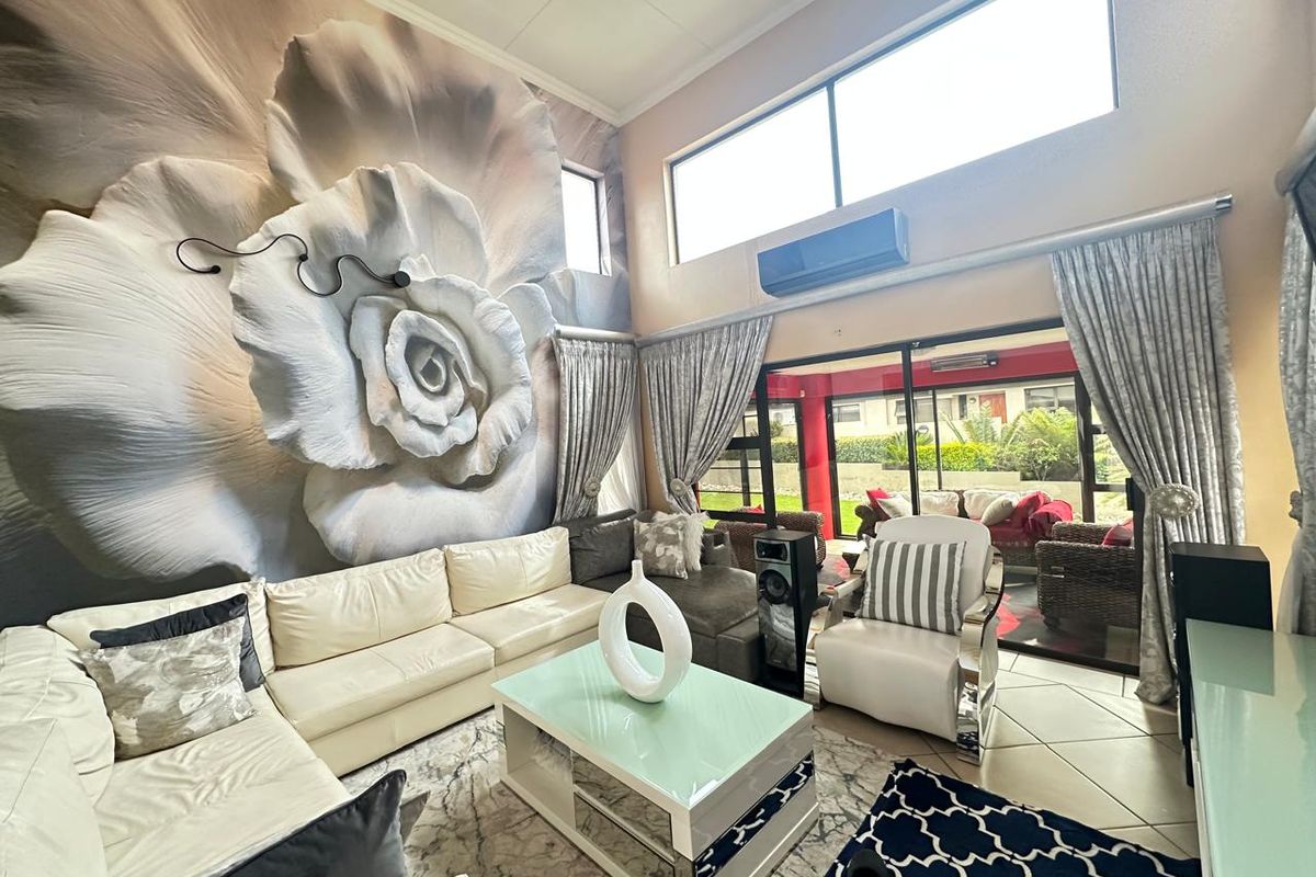 Spacious living room featuring high ceilings, large windows, wall-mounted air conditioning unit, and sliding glass doors leading to an outdoor patio area.