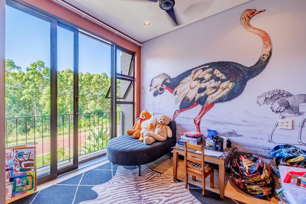 A bright bedroom featuring large sliding glass doors that open to a balcony, complemented by a decorative feature wall and recessed ceiling lighting.